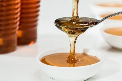 honey falling from a spoon in a small white bowl