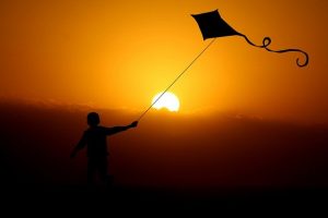 a boy flying a kite during sunset