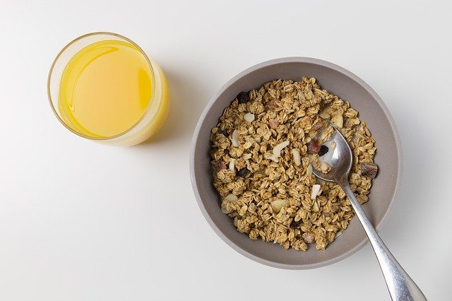 muesli in a bowl served with a glass of orange juice