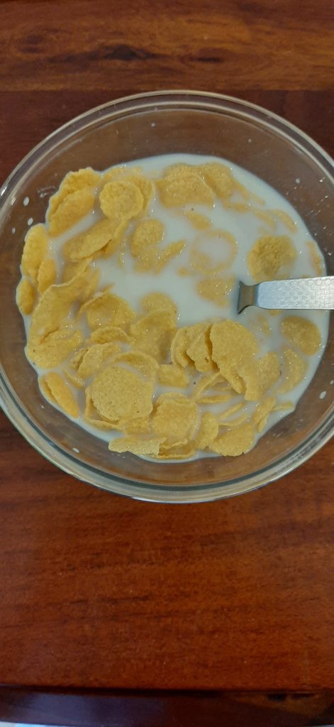 nestlé nesplus crunchy flakes with milk in a transparent glass bowl with a spoon