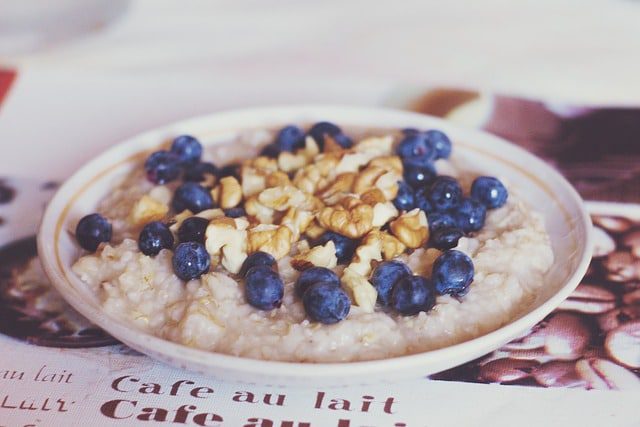 oats porridge in white ceramic bowl with blueberries on top