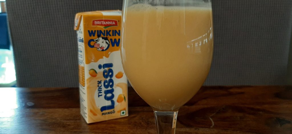 britannia winkin’ cow thick mango lassi poured in a transparent glass